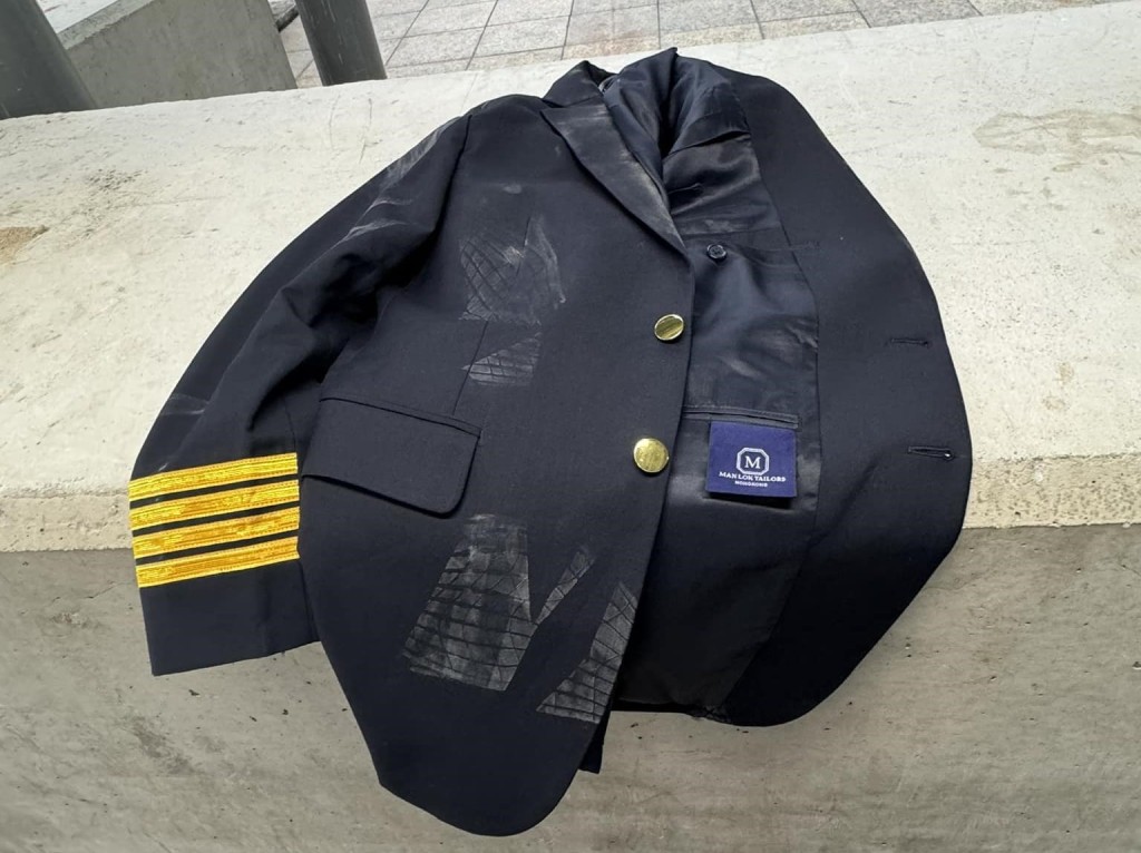 一件有四條金環刺繡相信是機長的制服，懷疑被遺留在機場擴建大樓外。網上截圖