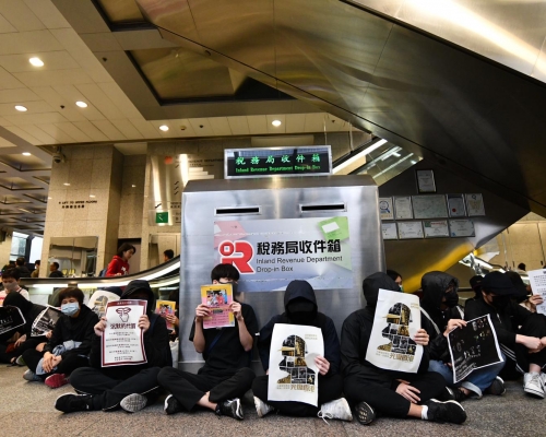有黑衣人在大樓大堂內靜坐。