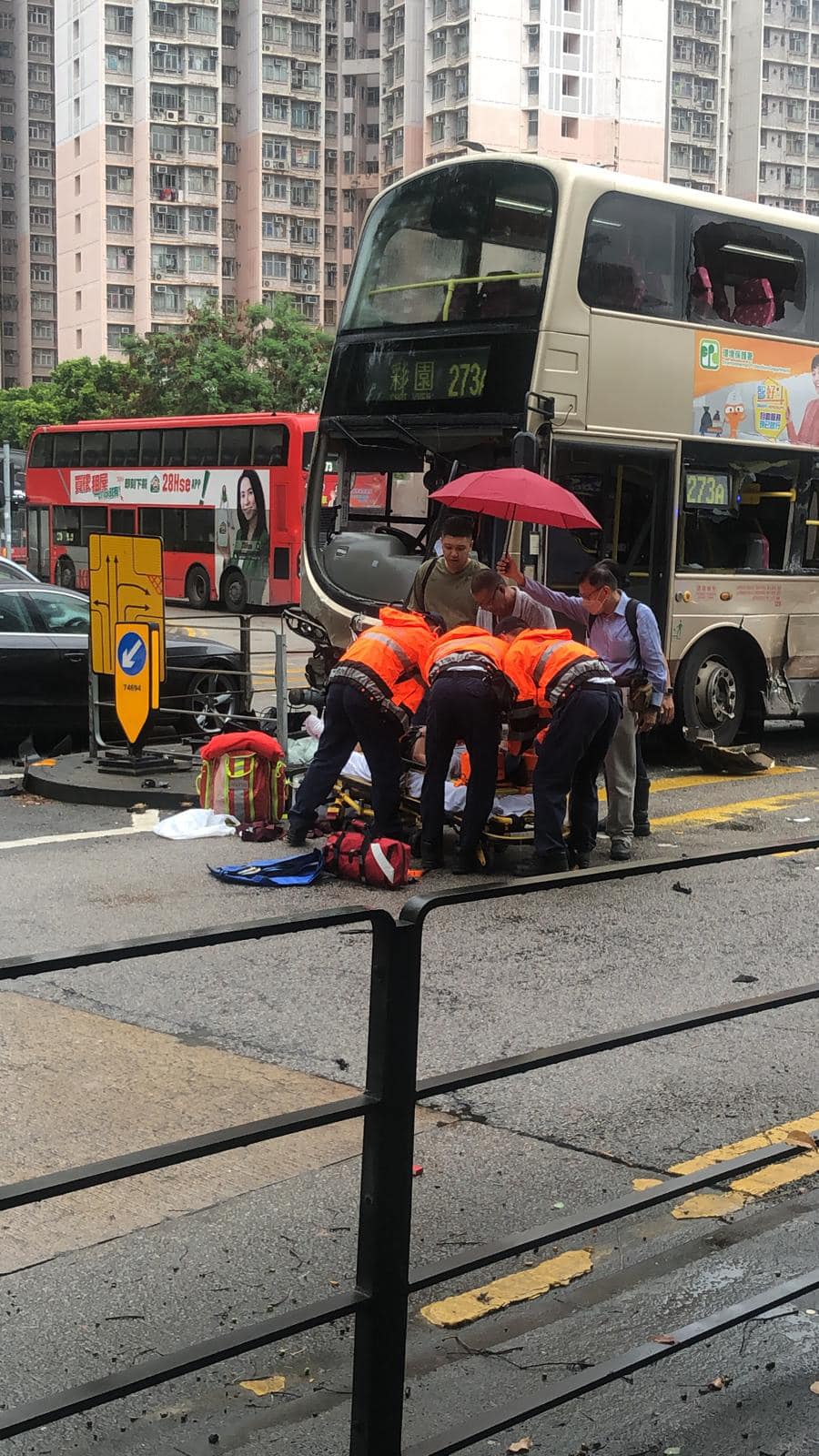 救護員為傷者施救，熱心途人打傘遮雨。網上圖片