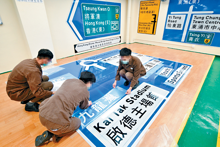 在囚人士將字體裱貼在大型交通標誌上。