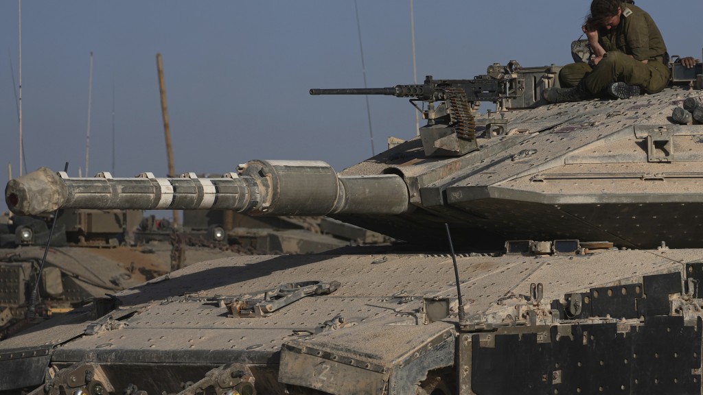 坦克集结在以色列南部加沙边境附近，一名女兵坐在坦克上。 美联社