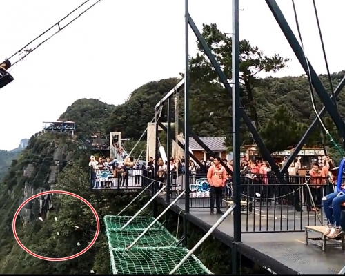 重慶一個男遊客體驗懸崖鞦韆時,口袋內的紙鈔意外跌出。影片截圖
