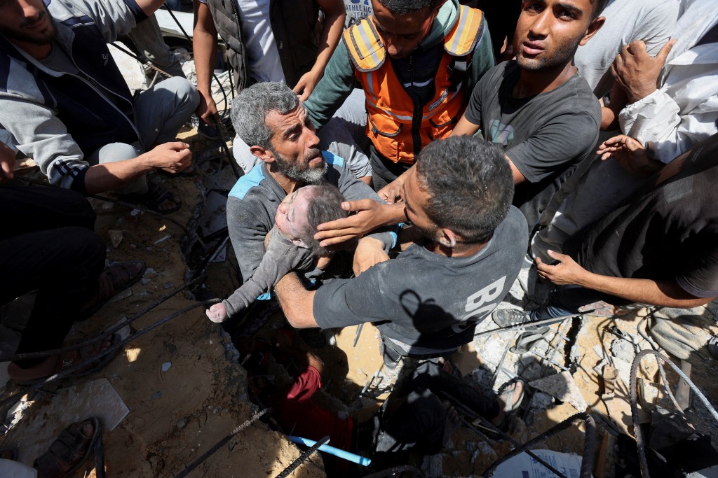 救援人员从被炸的联合国学校内抬出一名小童尸体。路透社