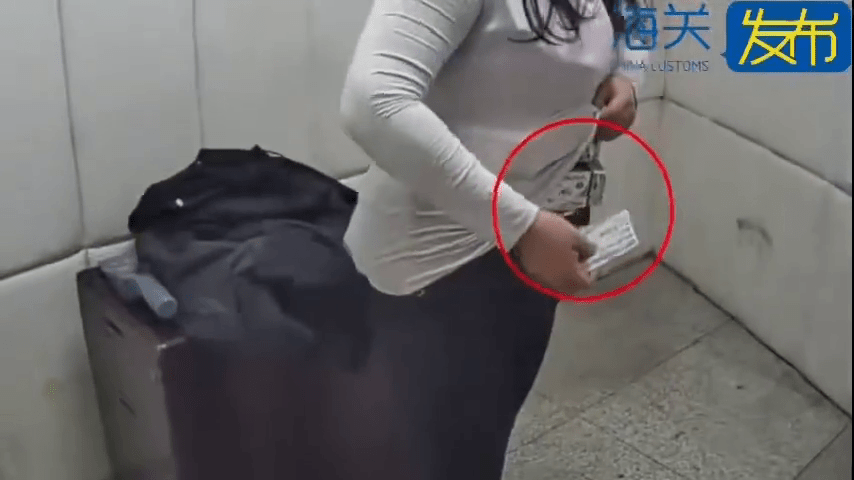女子从衣服内拿出“伟哥”。 海关发布 女子从衣服内拿出“伟哥”。 海关发布