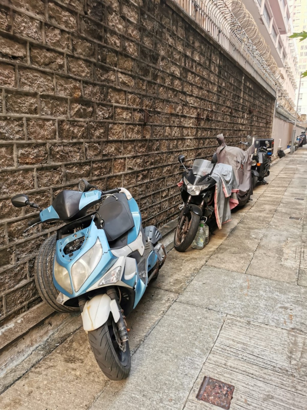 黃大仙翠鳳街後巷有逾十架電單車閒置已久，大多被除去車牌，塵土蓋滿。 阿熊提供