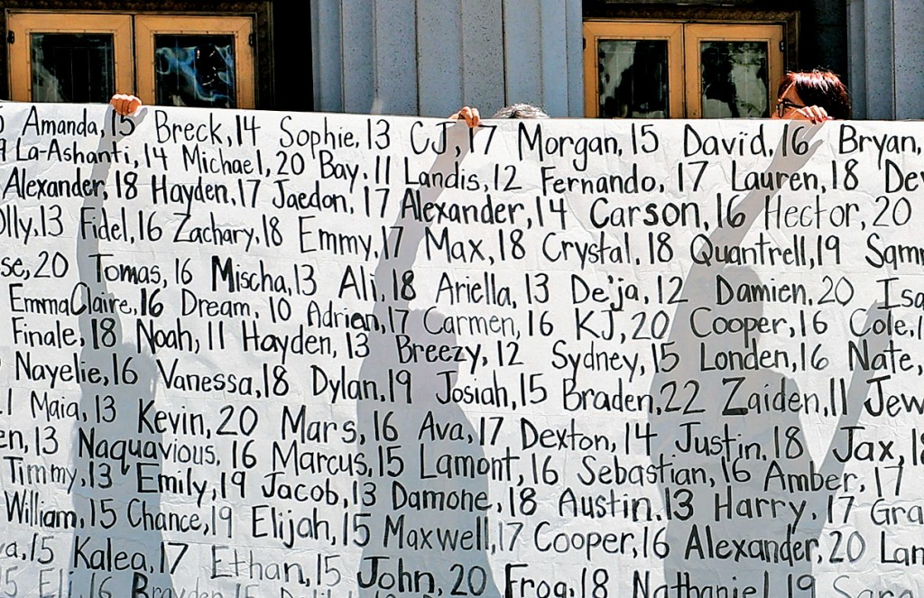 一些声称因社交媒体而失去孩子的父母在法院外举起写有孩子名字的横幅。