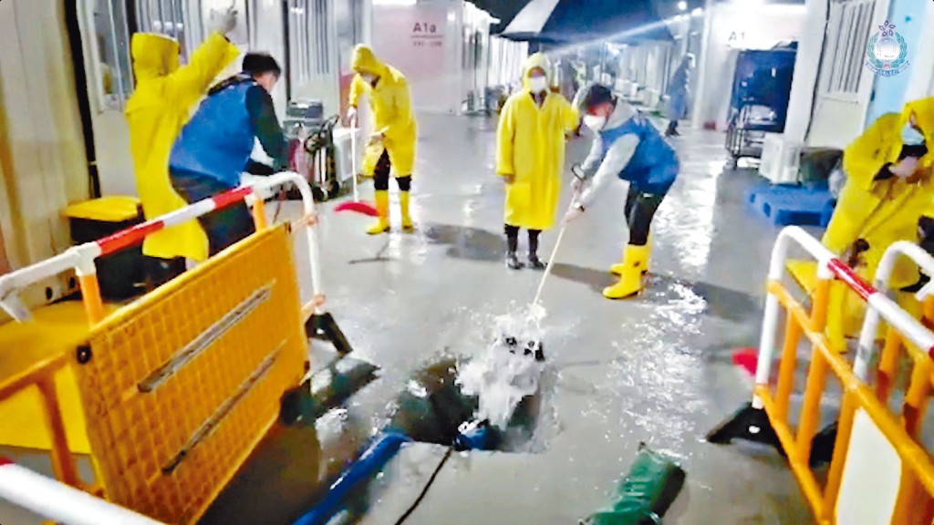 入境處人員無懼風雨，迅速清理地面積水。