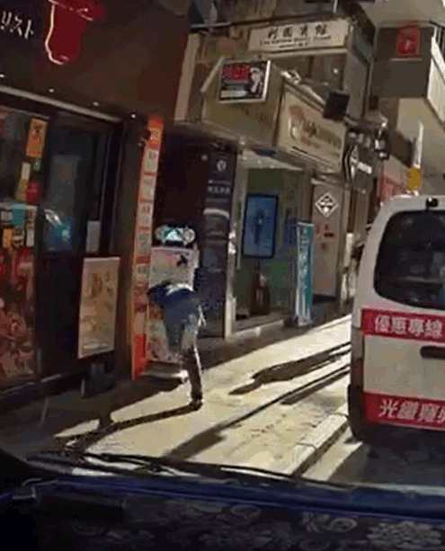 男子衝前撞倒放在路邊的直立式廣告牌。影片截圖