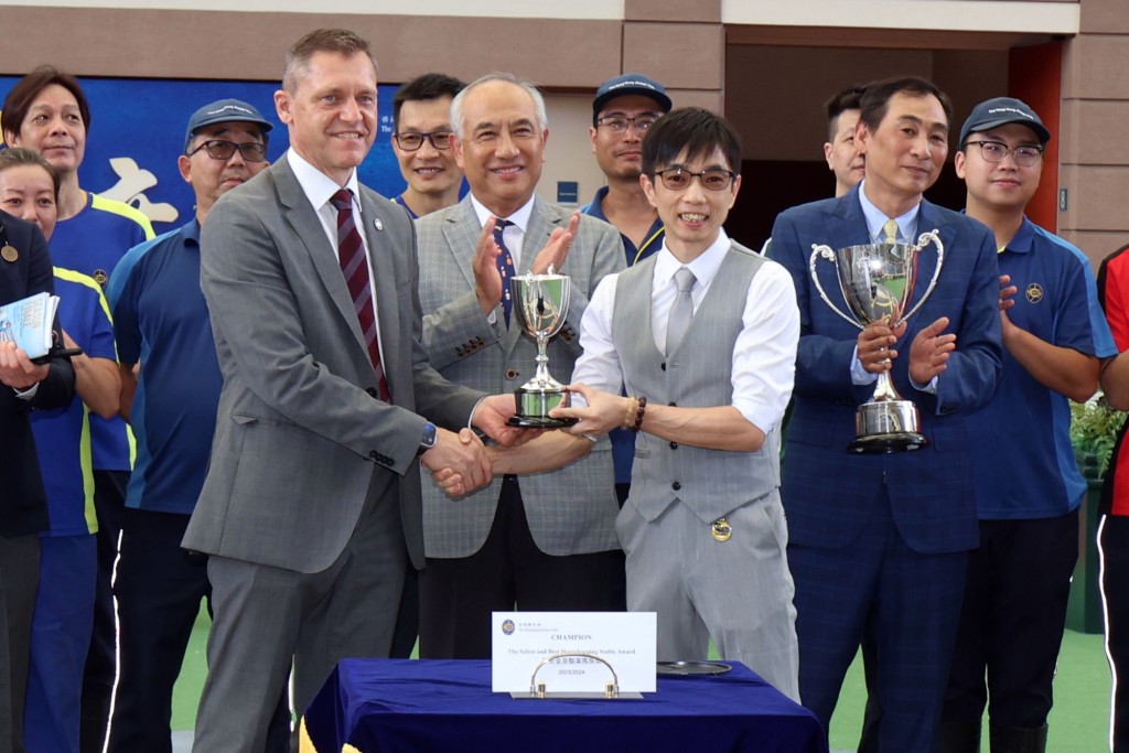 香港賽馬會賽馬營運總監魏德(左) 將「最安全及整潔馬房獎」的馬房獎項頒予鄭俊偉馬房的助理練馬師梁明偉(右)。