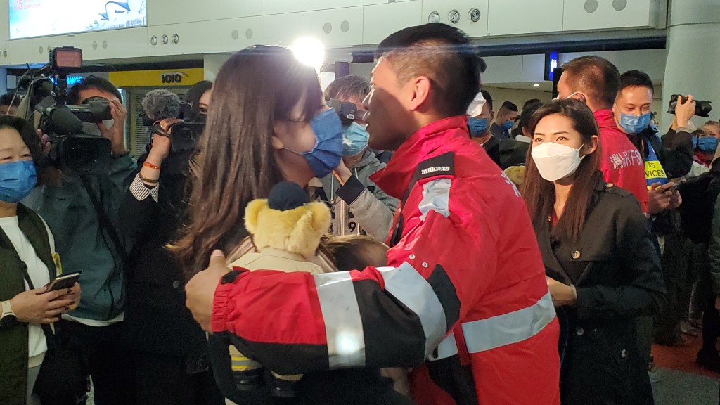 阔别9天，救援队队员刘文发与接机的妻儿相拥。尹敬堂摄