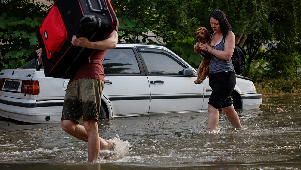 在烏克蘭赫爾松，卡科夫卡水壩決堤後，當地居民撤離時在一條被洪水淹沒的街道上走過。路透
