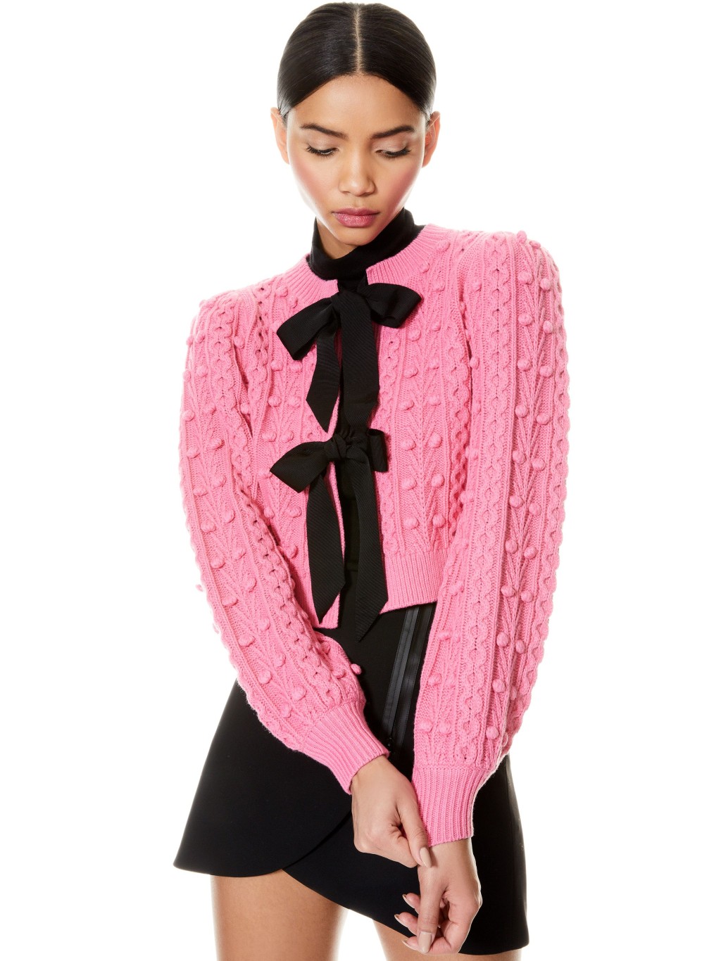 粉红色针织短身外套/$4,250/A，胸前饰以黑色双蝴蝶结，设计精致又女性化，下衬黑色迷你裙，充满少女味。