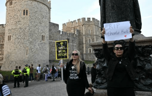 數十名示威者周二在溫莎城堡外高舉標語牌，抗議特朗普到訪英國，其中有人高舉紙牌，願日前遭槍殺的查理．柯克主懷安息。法新社