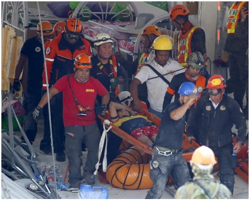 救援人员于瓦砾中救出3名生还者。AP 