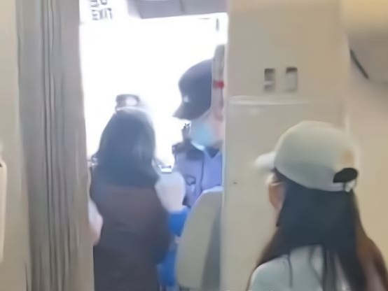 女子被押離機艙。網圖