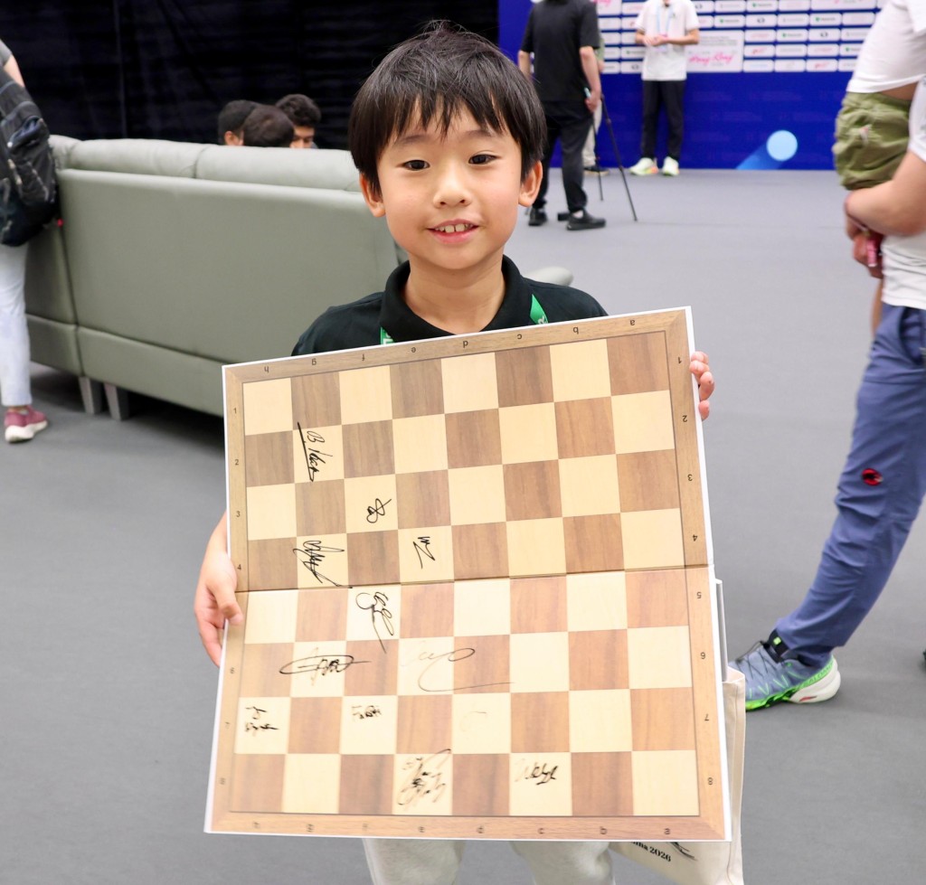 陈祉翺开心展示他得到的棋手签名。徐嘉华摄