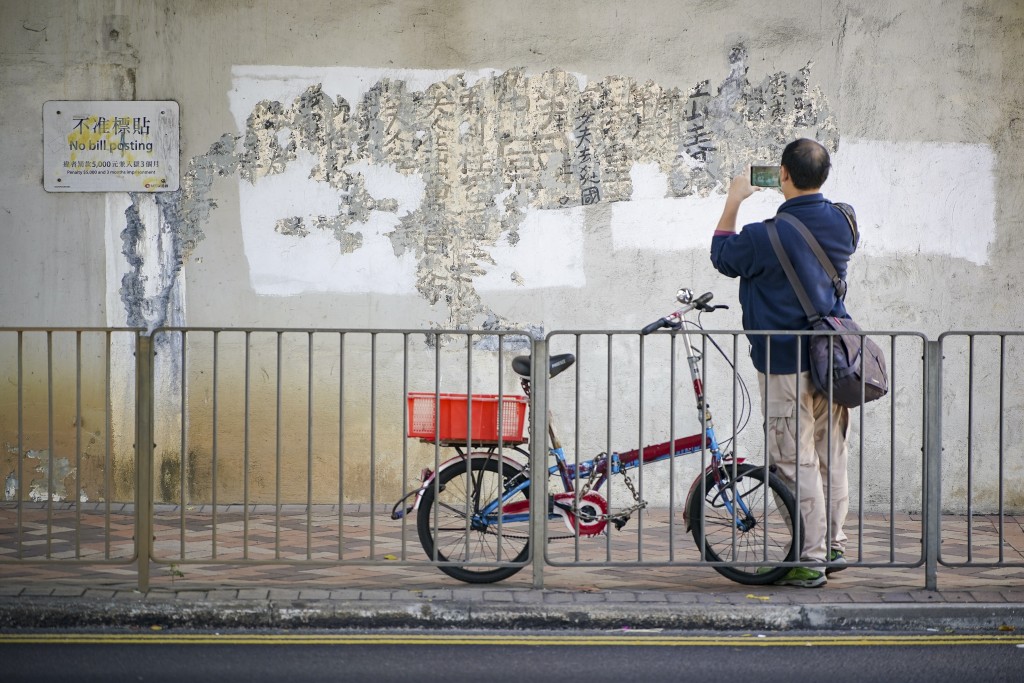 曾灶財是街頭塗鴉者，用毛筆書寫漢字進行創作，他留下墨寶吸引路人拍照。