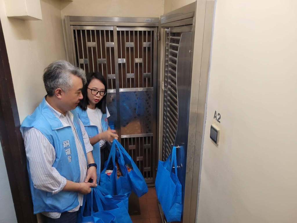 灣仔民政專員張雁伶(右)與關愛隊應居民所急，上樓家訪送上中秋福袋。
