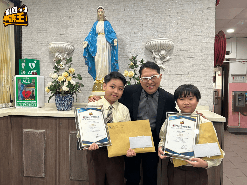 大角嘴天主教小學校長周德輝先生與兩位得獎同學俞綽帆（左）及林俊樂（右）合照留念。