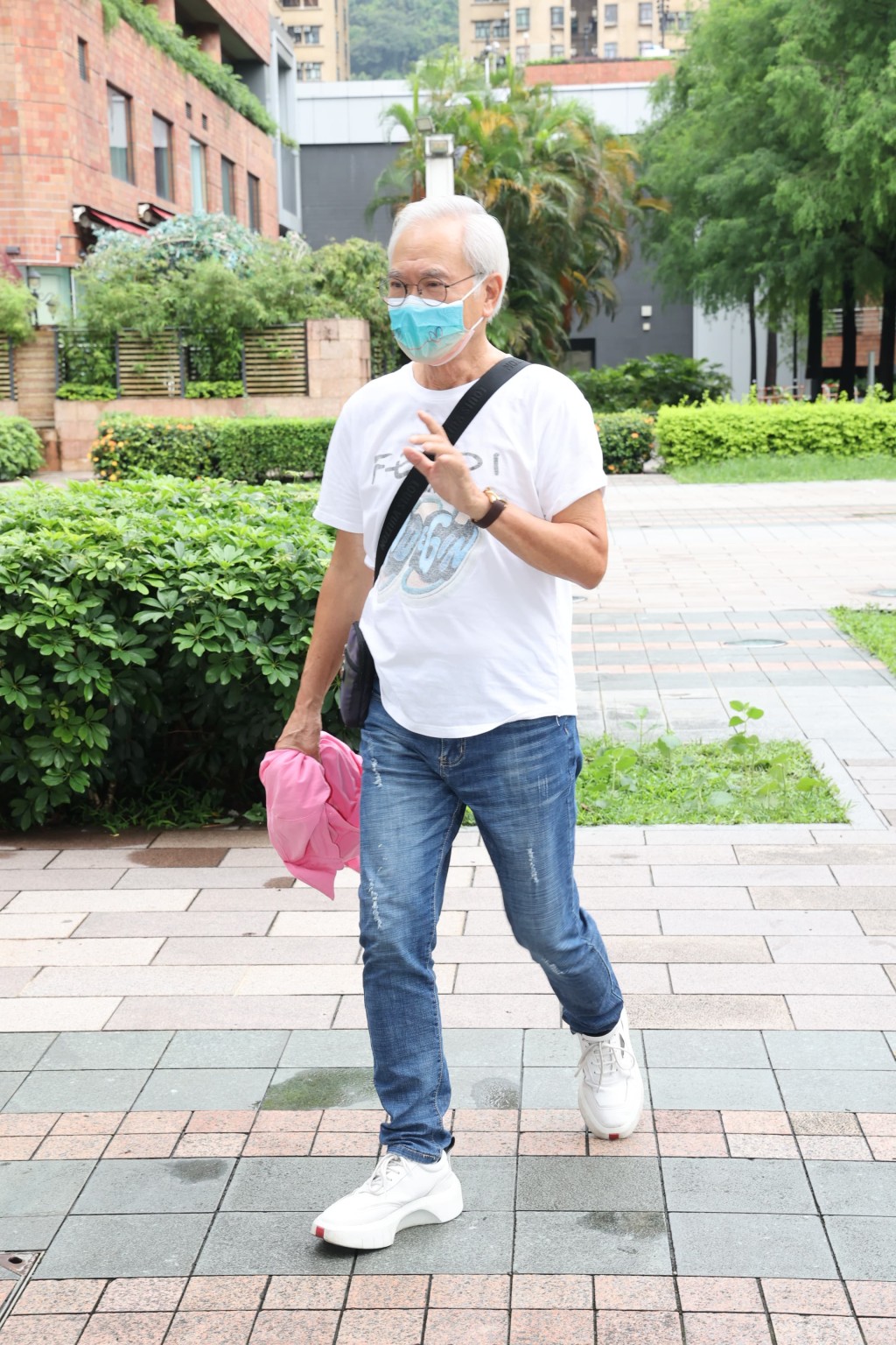 戴上口罩兼身穿「FENDI」白色T恤、拿著粉红色衣服的李龙基到达法院。