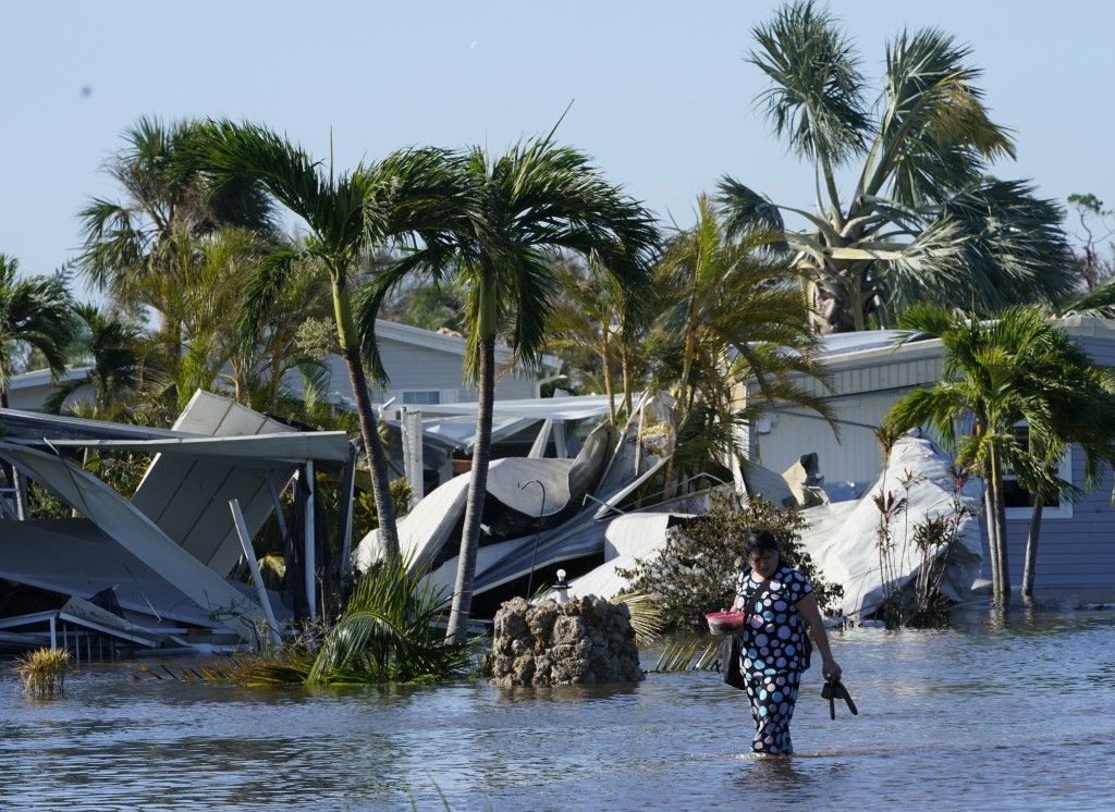 一名女子走出被洪水淹沒的社區。AP