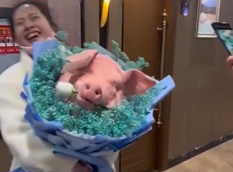 女子手捧重量级大紥猪头花出现。影片截图