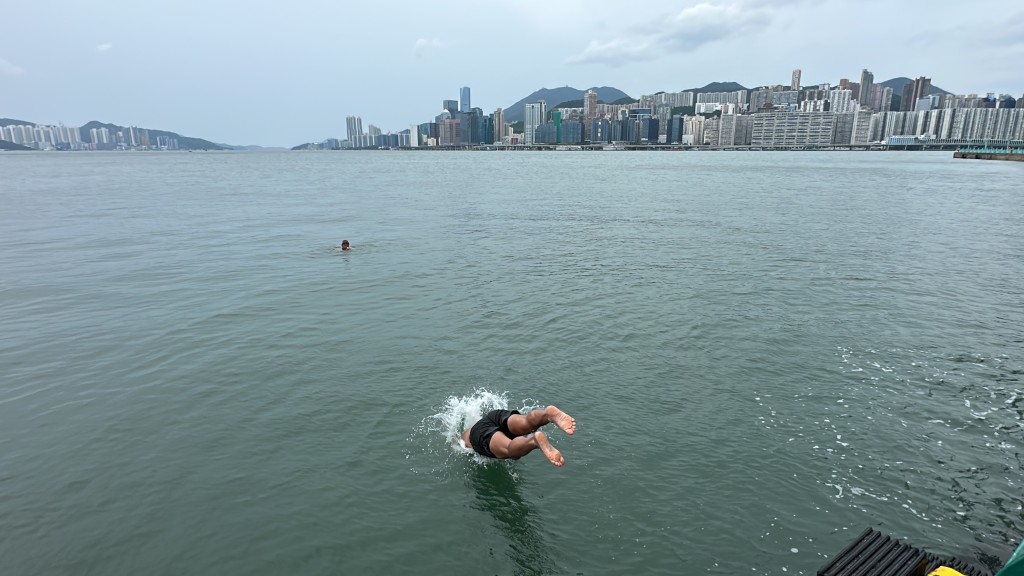 泳客无惧风雨游水。刘汉权摄