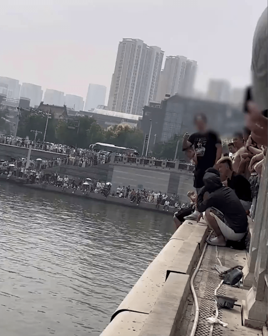 一名身穿黑衫的青年准备从桥上跳下水。