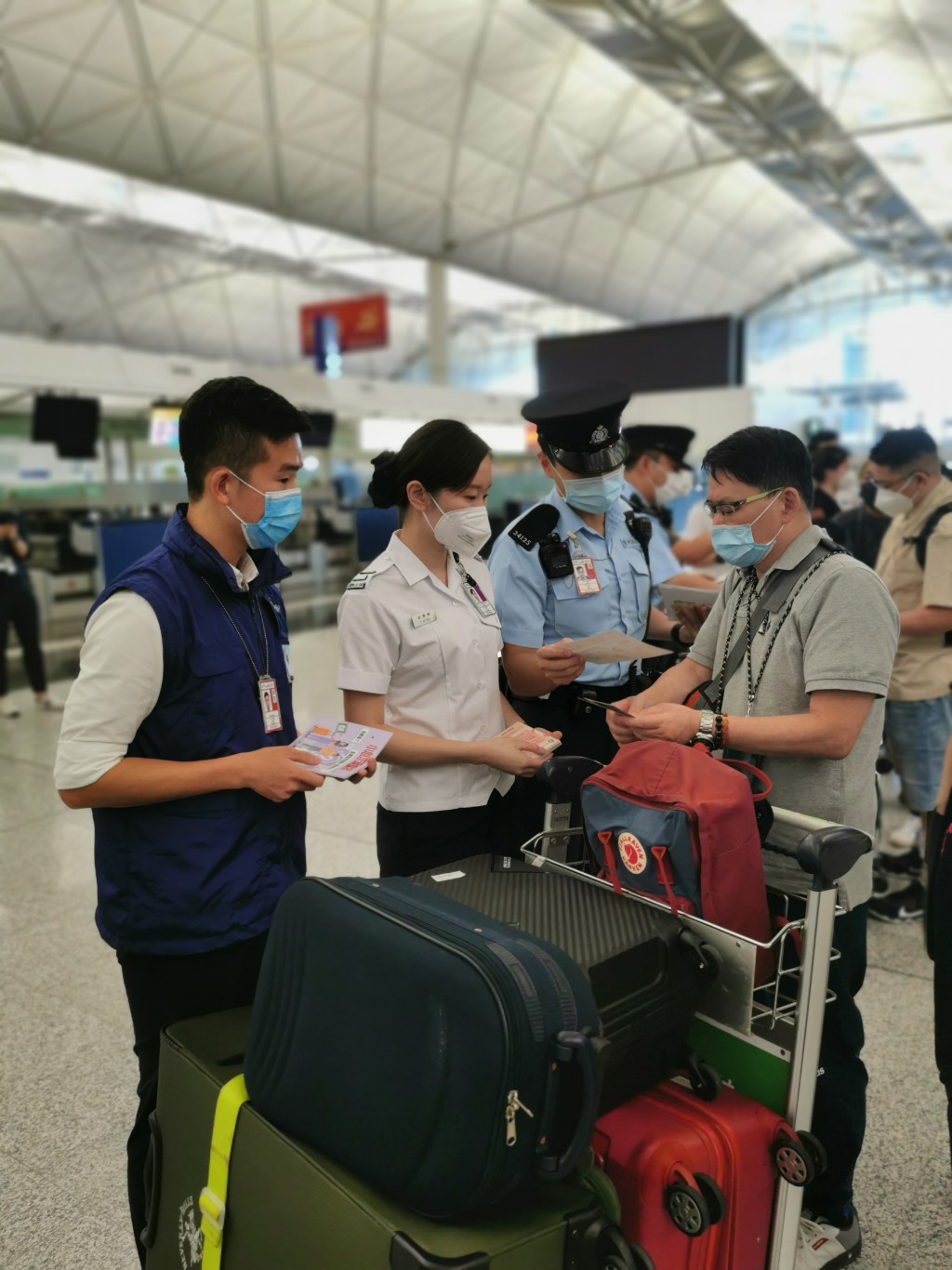 警务处和入境处人员在机场派发宣传单张，提醒离港旅客小心求职骗案及注意外游安全。