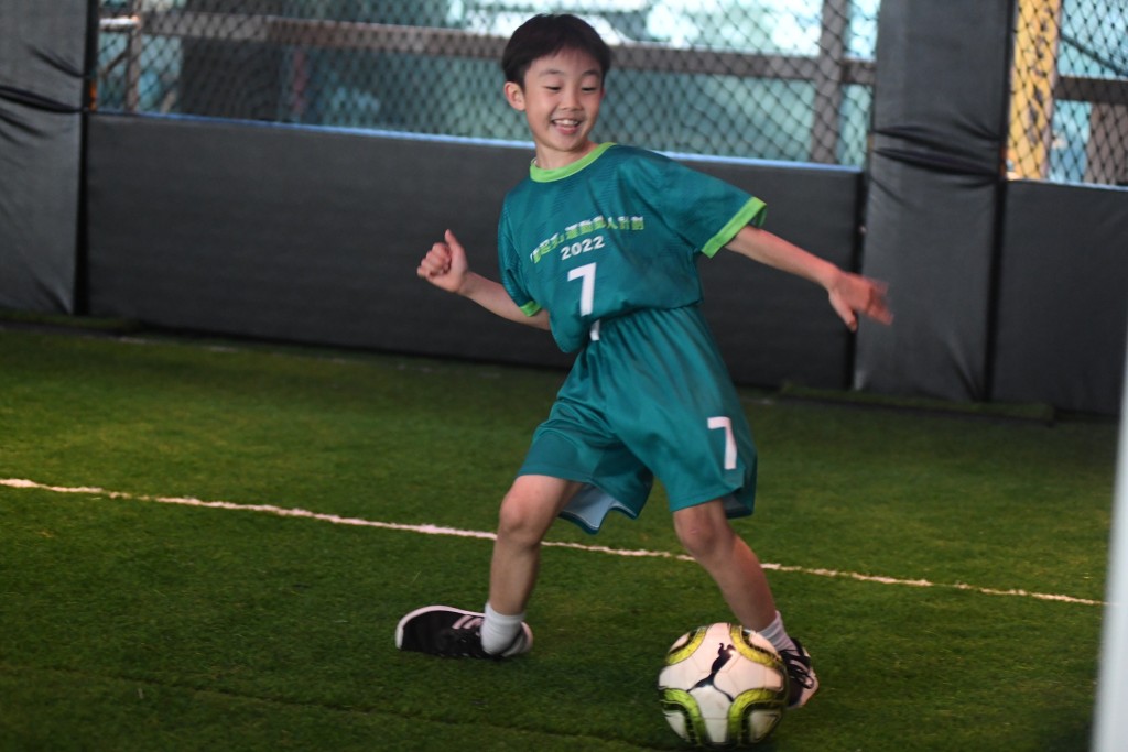 小孩子踢足球時笑容滿面。 本報記者攝
