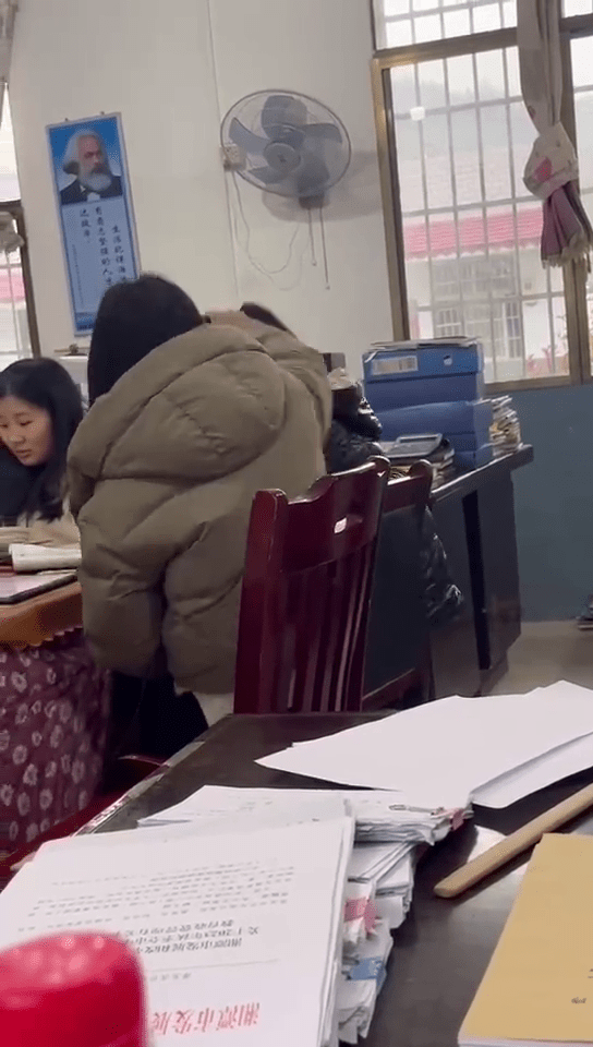 女老师拉扯女学生的马尾狂摇，近乎将学生头部撞向桌面，画面令人不适。