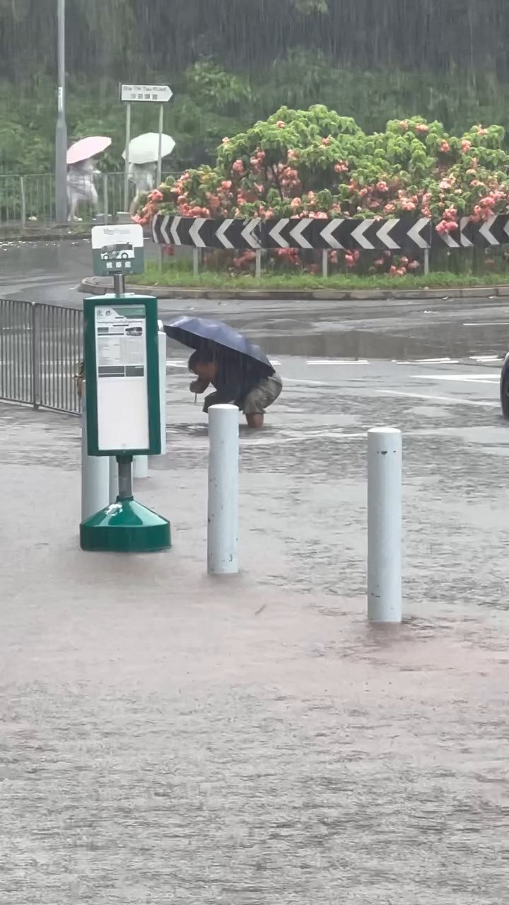 一名中年男子冒着大雨伸手落積水清走垃圾。threads@_.yuching