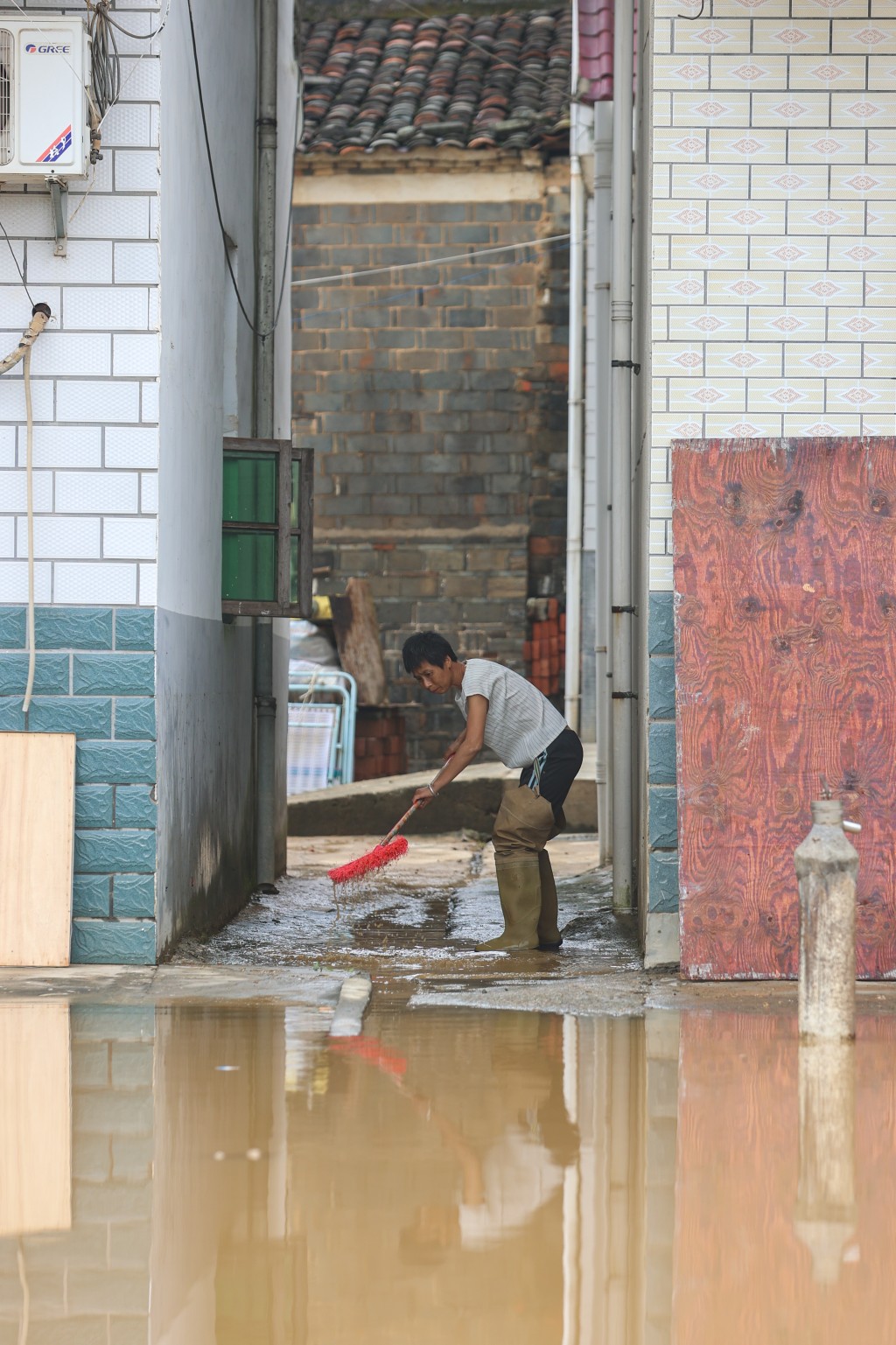 5月7日，江西宜春市梘口村，一位村民在房屋邊清掃污水淤泥。(中新社)