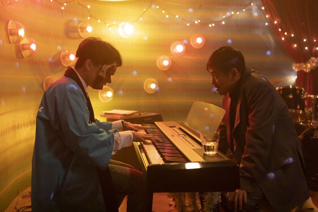 年輕鋼琴師博（左），應神秘的黑道中人（右）所求，彈奏電影《教父》主題曲。