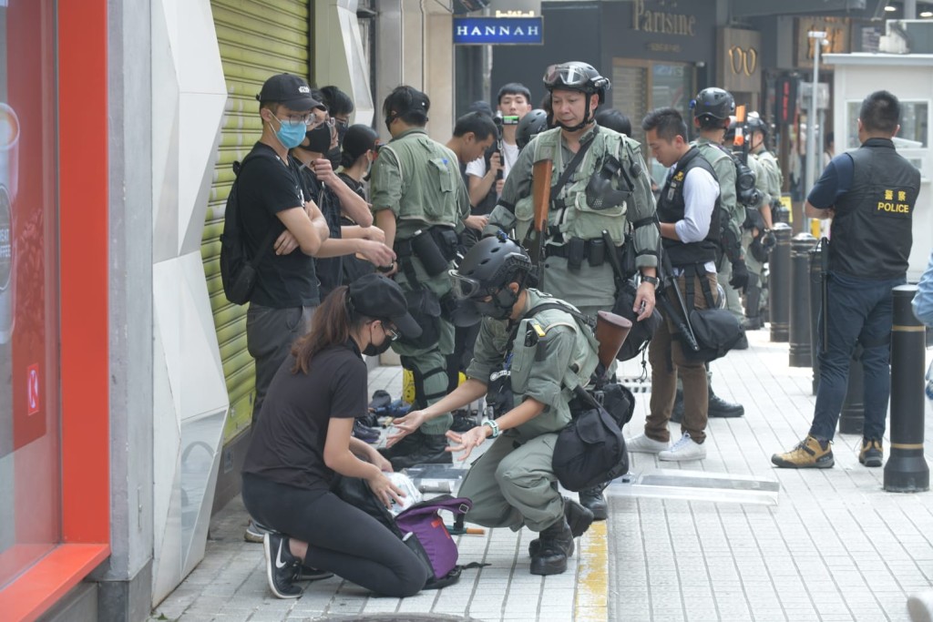 防暴警搜查在場的黑衣人士。