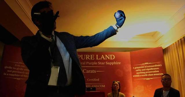 寶石學顧問阿馬拉辛格拿起這顆藍寶石欣賞。美聯社