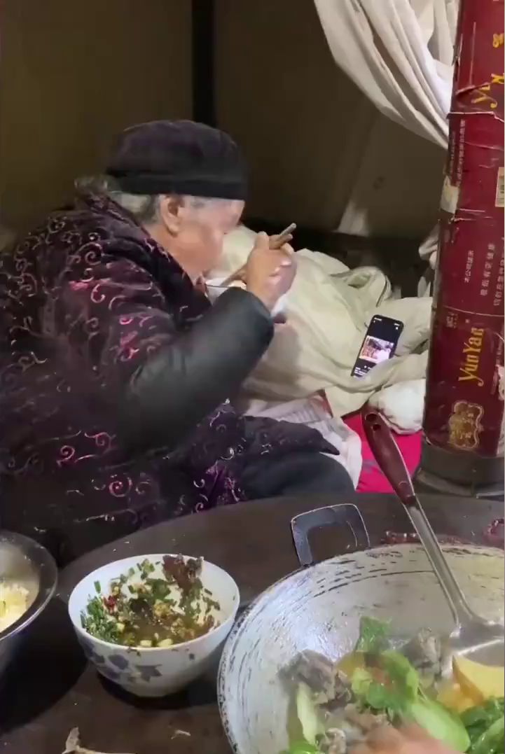 88歲的老婆婆邊看手機邊吃飯。