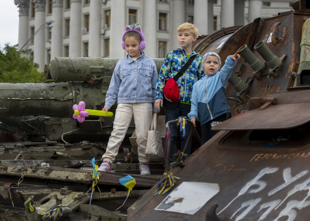 孩子们站在乌克兰基辅圣迈克尔广场烧毁的俄罗斯坦克上。路透
