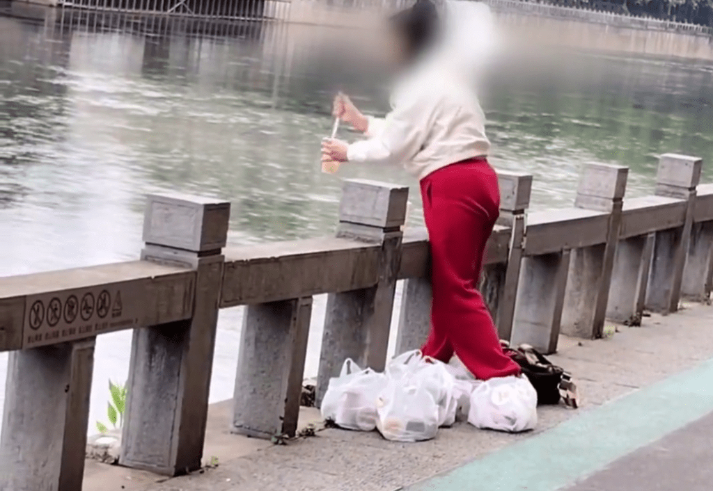 貴州女子在河邊將一杯一杯的奶茶「放生」。