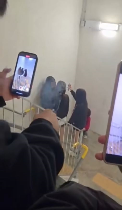 同黨在樓梯高處圍觀，有人一邊抽煙一邊拍片。網片截圖