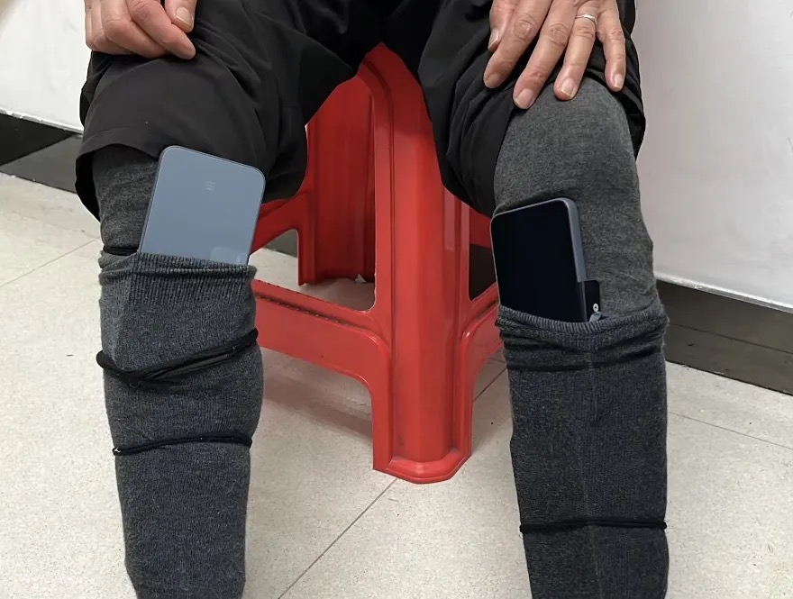 手機以用灰色長襪和橡筋固定在小腿位置。