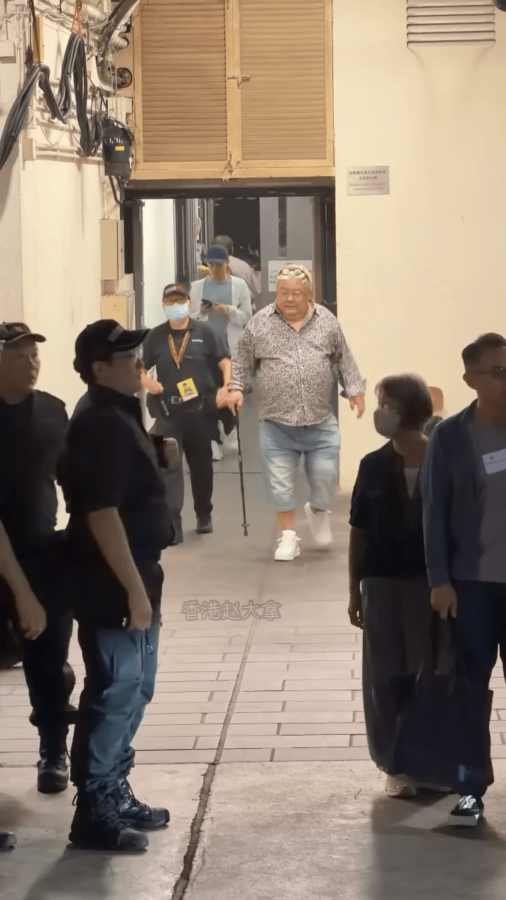 林雪身形依舊龐大，右手撐著拐杖、行動顯得相當緩慢且吃力。