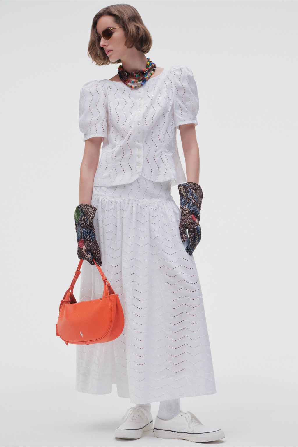 Head-to-toe的纯白造型，大胆配衬橙色手袋、图案手套及Mulit-colour珠串项链，满满的时装感。（Polo Ralph Lauren）