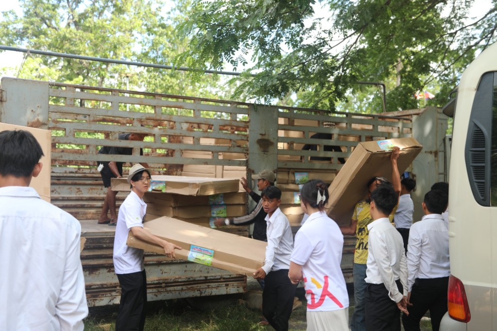 林皓峯（戴帽）與當地居民合力搬運物資。 共享基金會提供