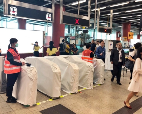 在將軍澳站，港鐵職員持手提八達通機在出入口協助乘客拍卡出入閘。
