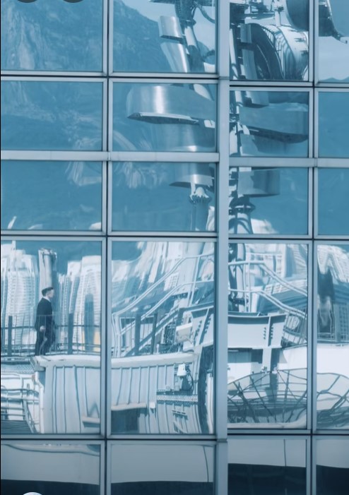 鏡頭拍攝對面大廈的灰綠色反光玻璃,反射李百全行上天台時的畫面。 鏡頭拍攝對面大廈的灰綠色反光玻璃,反射李百全行上天台時的畫面。