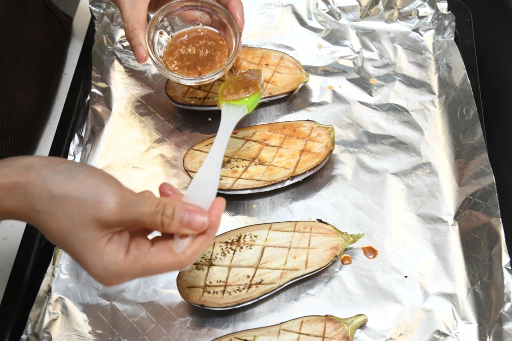 Step 6: 取出茄子，在表面涂上调味料。 Take out the eggplant and brush the seasoning on top.