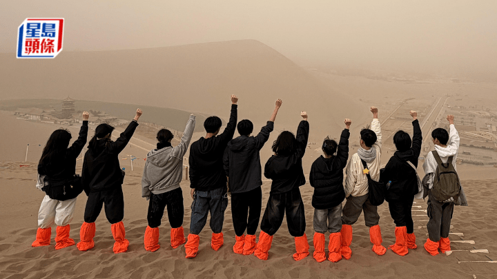 與組員同登鳴沙山，遠望月牙泉，心生滿滿成就感。（作者提供）