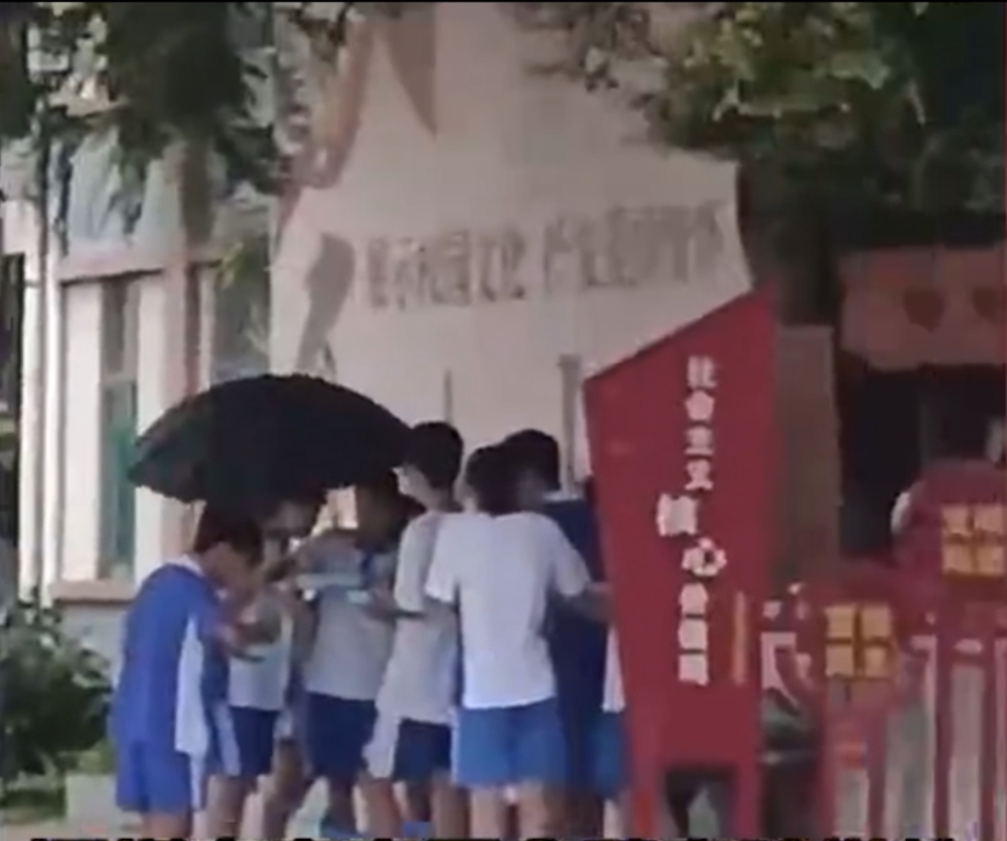 7、8個孩子撐着傘、站着吃飯。