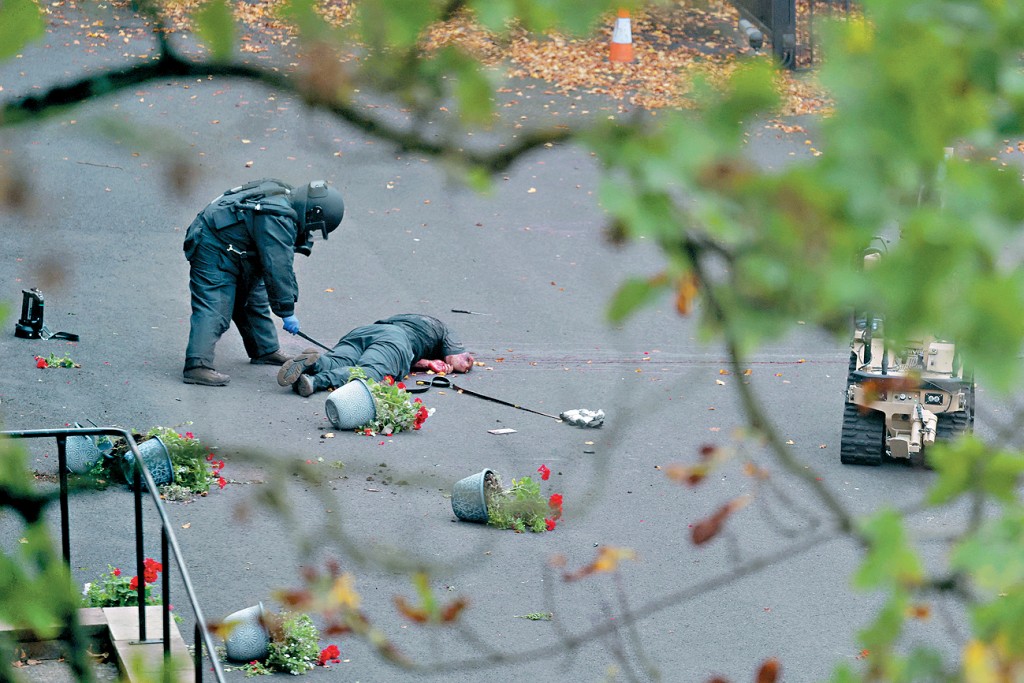 身藏不明物的疑兇被警員開火擊中伏地，警方拆彈專家和機械人到場調查。